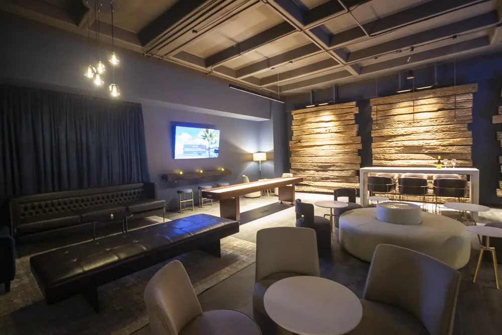 Lounge social con barra, mesas y pantalla