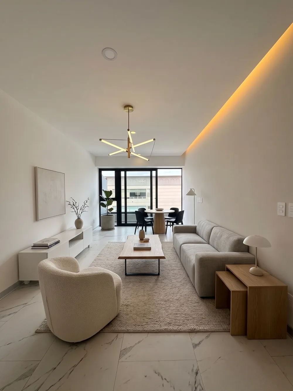 Sala con iluminación cálida indirecta y comedor al fondo